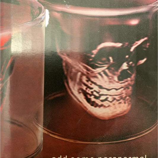 A shot glass with a design of a skull, marketed with the text 'ADD SOME PARANORMAL TO YOUR NEXT PARTY'.