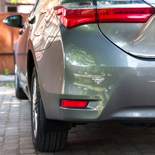 A close-up image of a car's rear bumper with a bubble-free sticker applied to it that reads 'Don't Worry About It'.