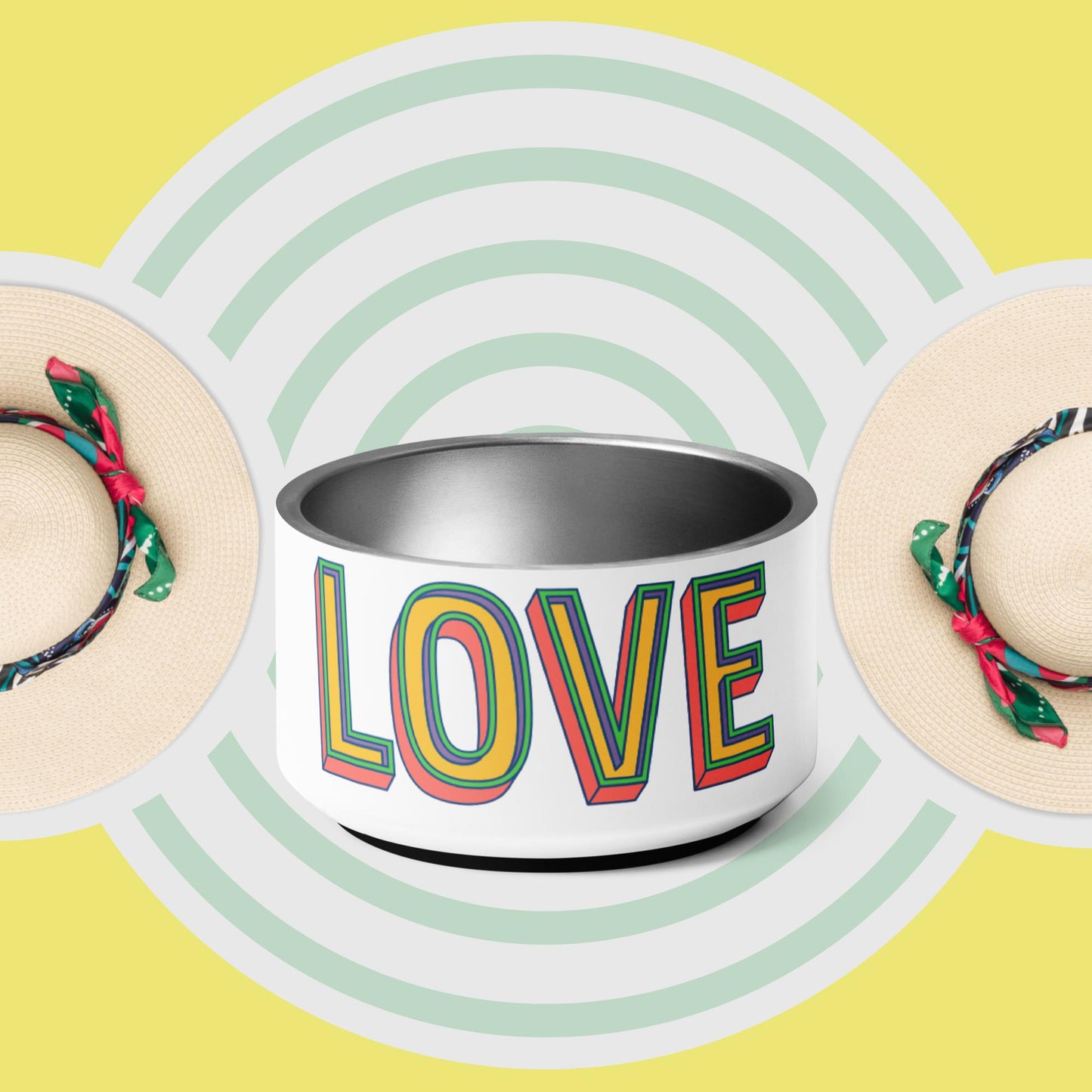 A stainless steel pet bowl with the word 'LOVE' printed on the side, set against a yellow background with a pattern of green concentric circles. The bowl has a double-wall design and anti-slip rubber base.