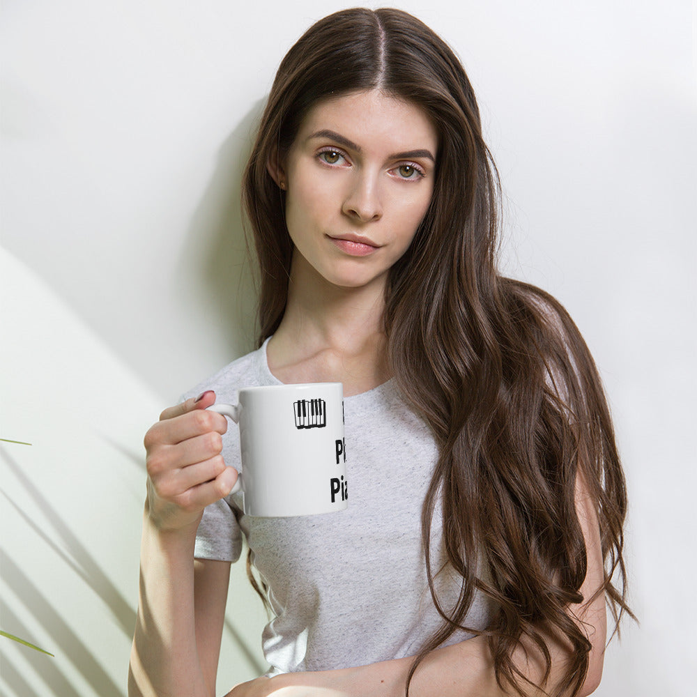 A person holding a white ceramic mug with the text 'I Play Piano' printed on it.