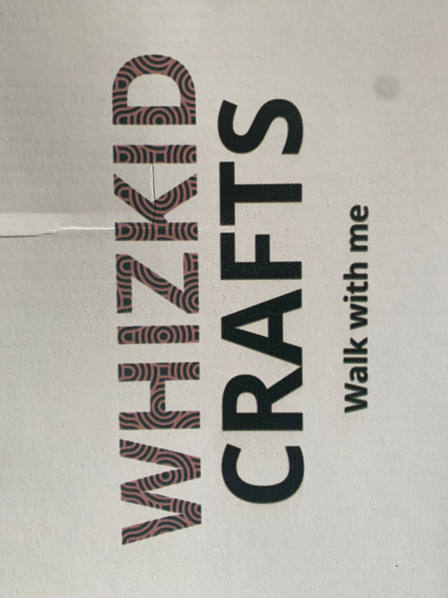 A close-up of a textile product with the words 'WHIZKID CRAFTS walk with me' printed on it, indicating a branding pattern.