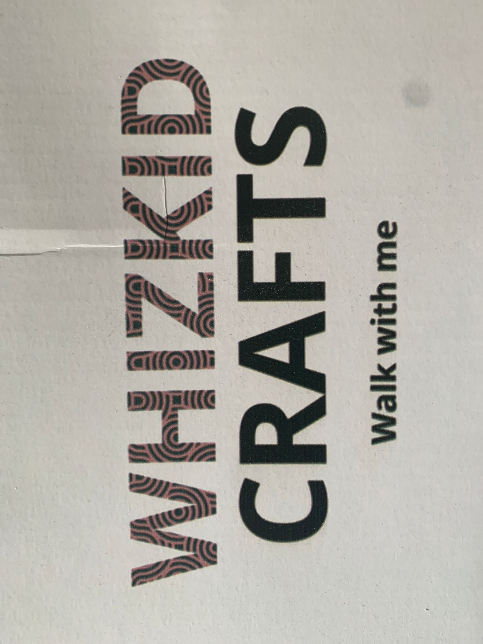 A close-up of a textile product with the words 'WHIZKID CRAFTS walk with me' printed on it, indicating a branding pattern.