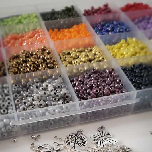 A collection of glass beads in various colors neatly organized in a plastic container, with some beads scattered outside the container.