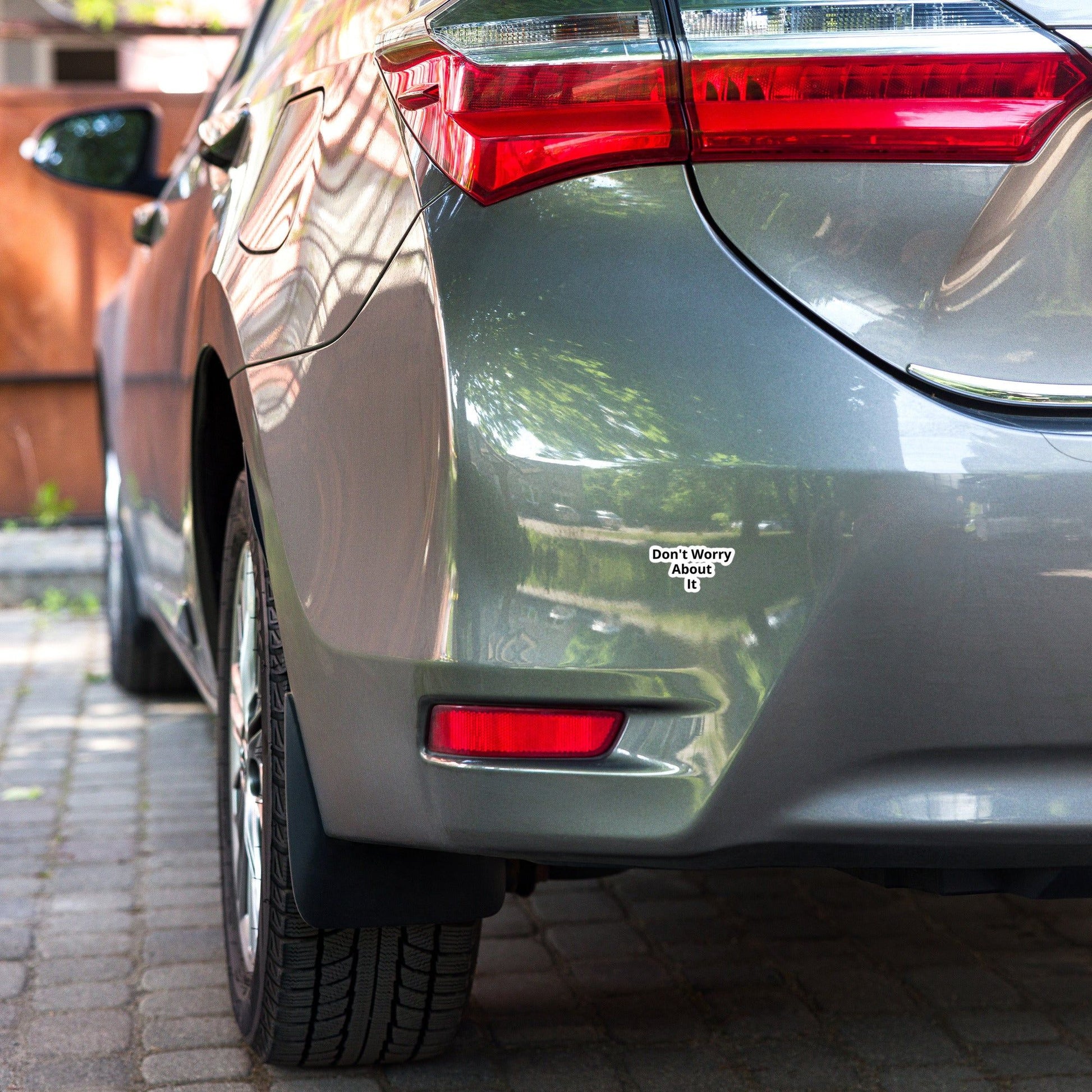 A close-up image of a car's rear bumper with a bubble-free sticker applied to it that reads 'Don't Worry About It'.