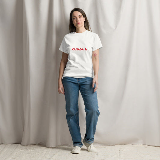 A person standing in front of a neutral backdrop wearing a white crew neck t-shirt with the text 'CANADA 1ST' on the front and blue jeans.