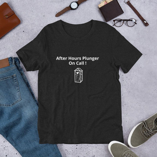 A black t-shirt with the text 'After Hours Plunger On Call!' printed on the front, laid flat with casual clothing items around it.